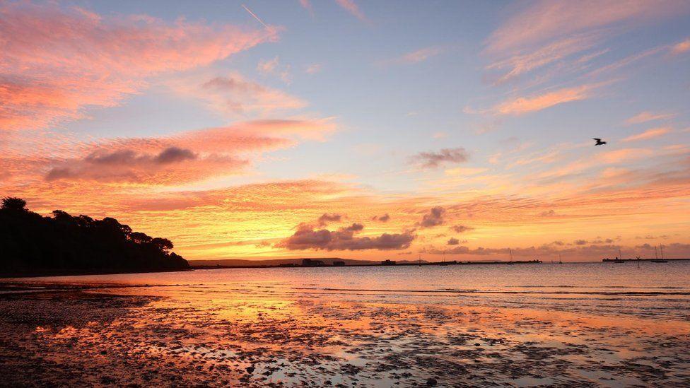 Orange and gold reflections at low tide with a scattering of pink and orange clouds