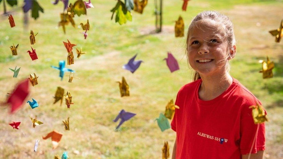 Child hangs origami peace cranes