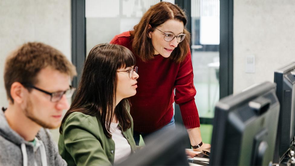 A teacher helping a student with her computer work during a lesson