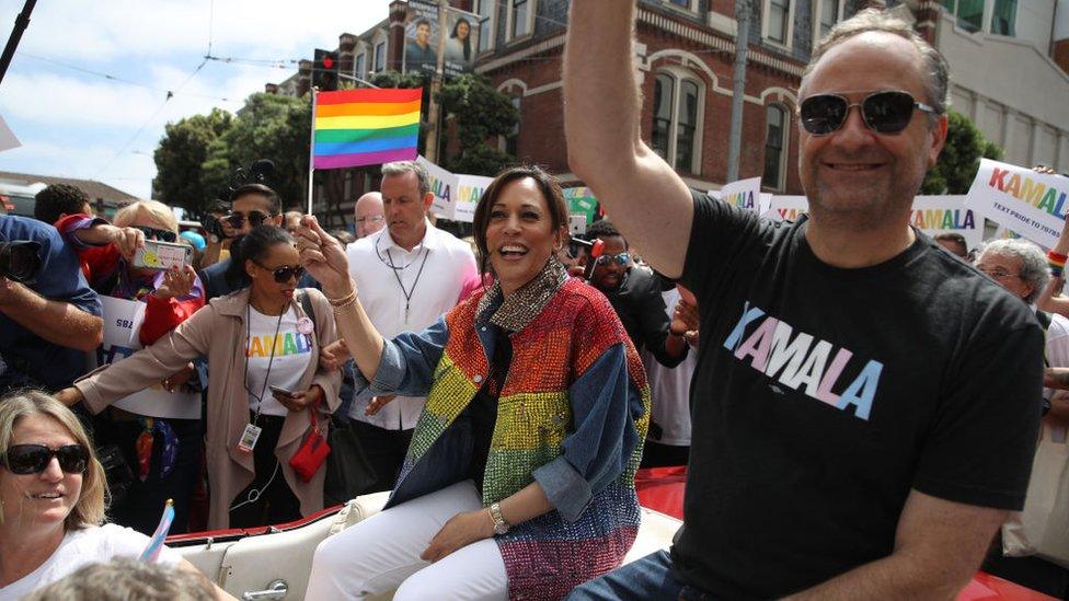 Kamala Harris and her husband Douglas Emhoff wave to the crowd as they ride in a car during the SF Pride Parade on June 30, 2019 in San Francisco, California