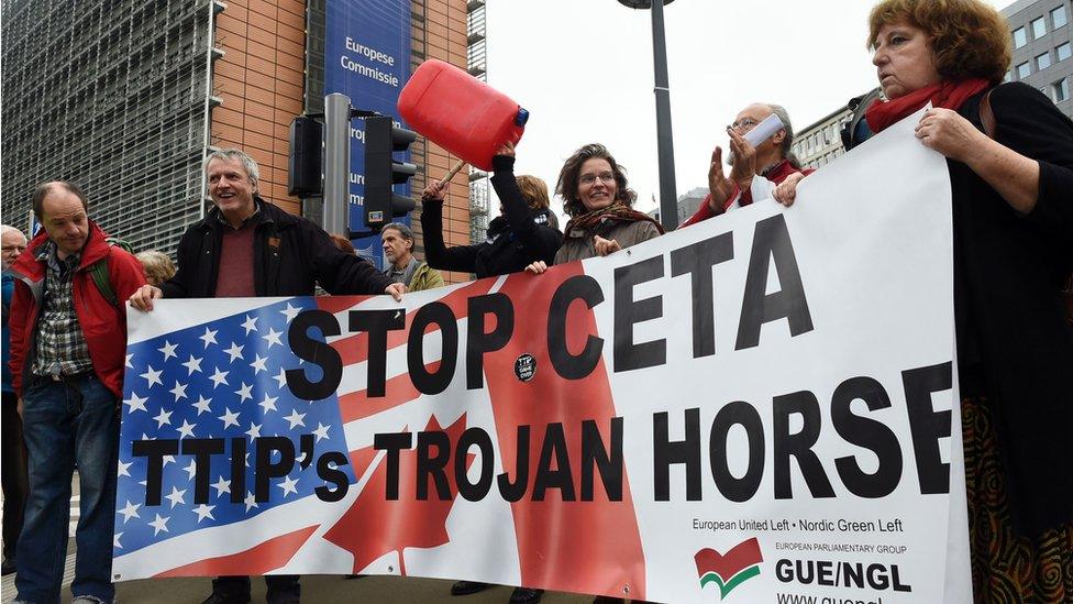 People hold a banner reading 'Stop EU-Canada Comprehensive Economic and Trade Agreement (CETA), Transatlantic Trade and Investment Partnership (TTIP)'s trojan horse' during a protest against the CETA at European Union Commission headquarters in Brussels on October 27, 2016.