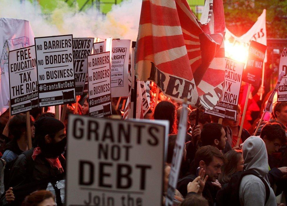 Students hold placards, flags and flares at the protest in London