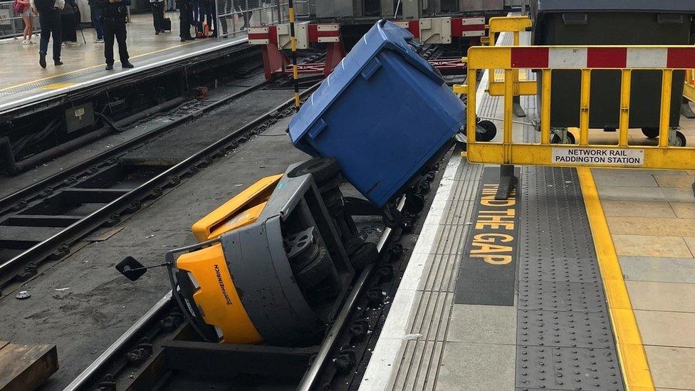 A rubbish dumpster and the vehicle towing it blocking platform one at Paddington