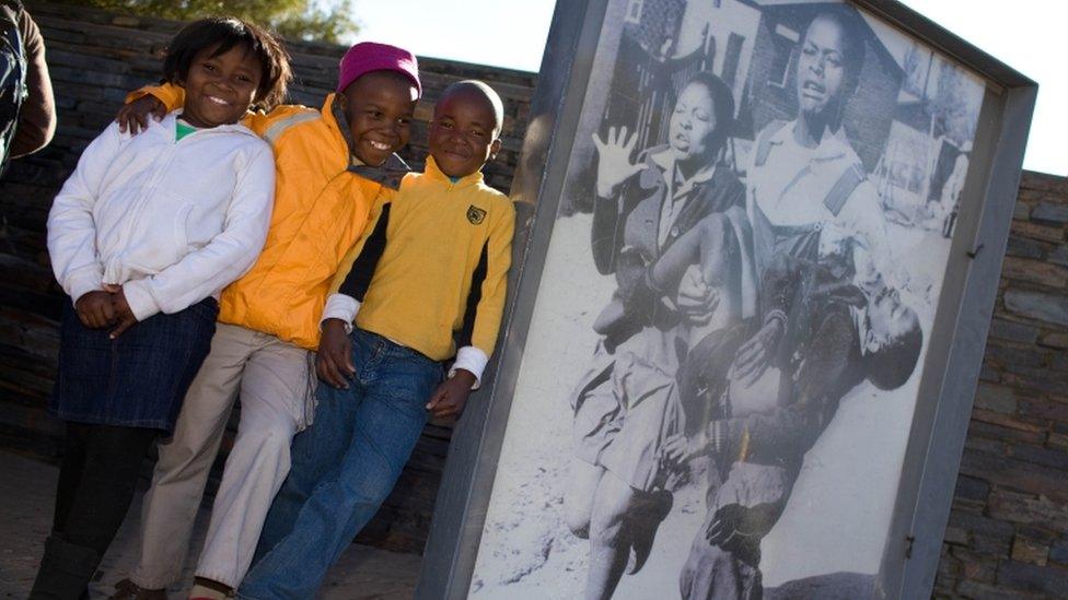 South African children pose next to the famous photo of 13-year-old Hector Pieterson being carried by students at Hector Pieterson Museum in Soweto on 16 June 2010