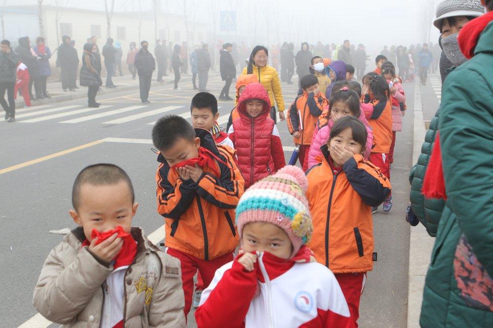 Pupils cover their noses after school in heavy smog on 23 December 2015 in Binzhou, China.