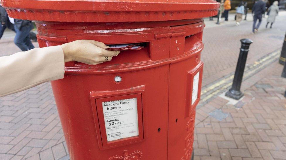 Someone posting letters through a red postbox