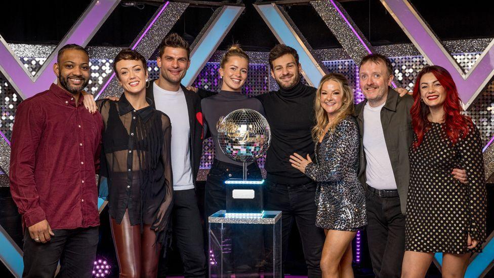 The eight Strictly finalists posing with the glitterball trophy in the studio before the final