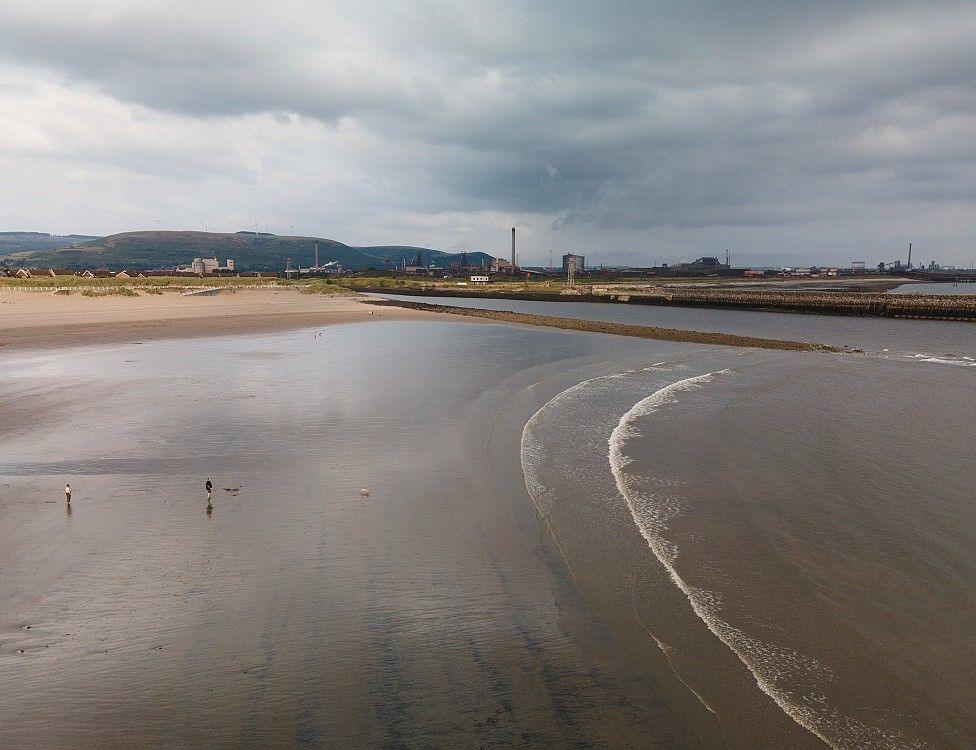 A drone shot of Aberavon beach with some views of Port Talbot steelworks in the background