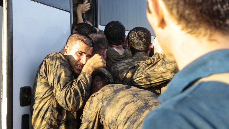 A soldier cowering as he is confronted by a man