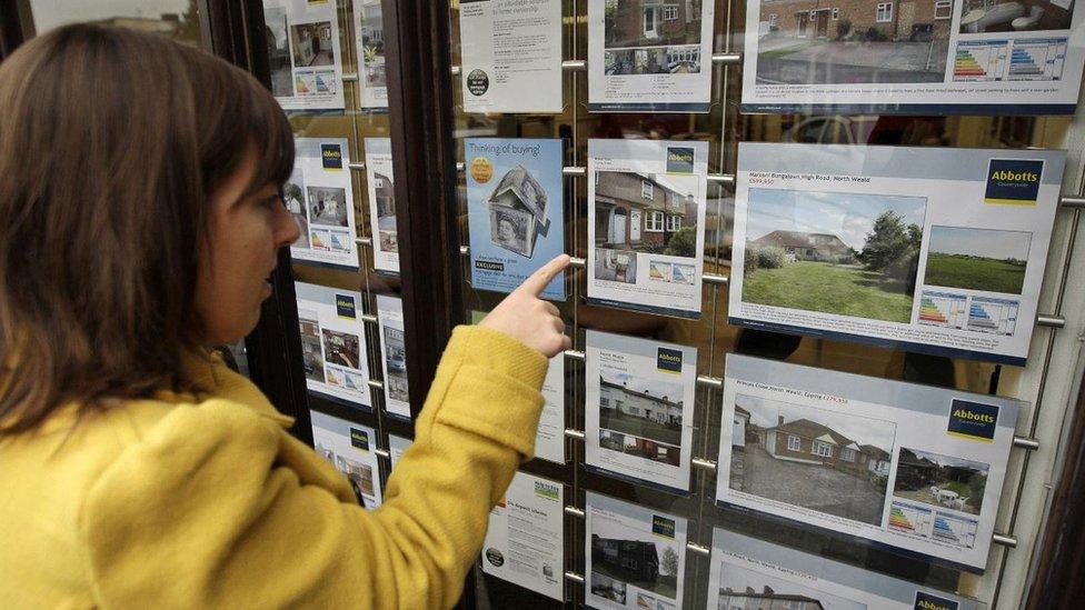 Woman looking in estate agent window