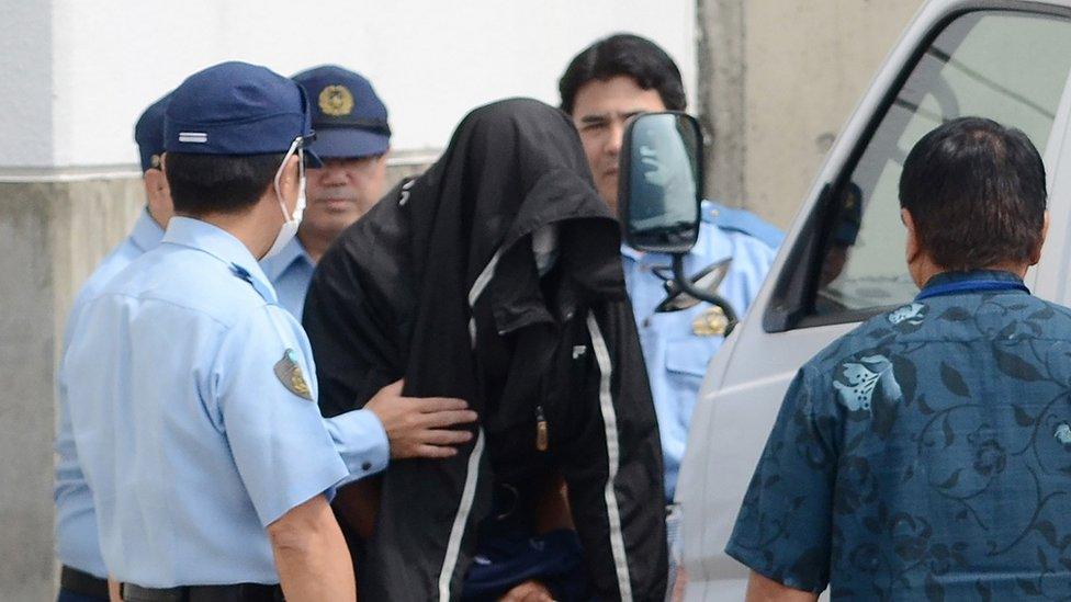 Policemen escort US citizen and former US Marine Kenneth Franklin Shinzato (C) to the prosecutor's office at Uruma Police Station in Uruma, Okinawa prefecture, on 21 May 2016.