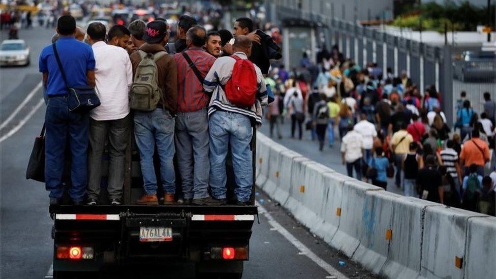 People ride in a truck and walk on a street during a blackout in Caracas, Venezuela February 6, 2018.