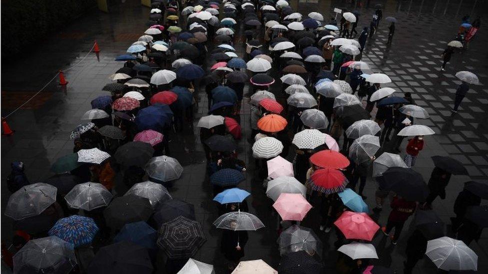 People queue in the rain outside a court in Yokohama on January 8, 2020, to attend the trial of Satoshi Uematsu