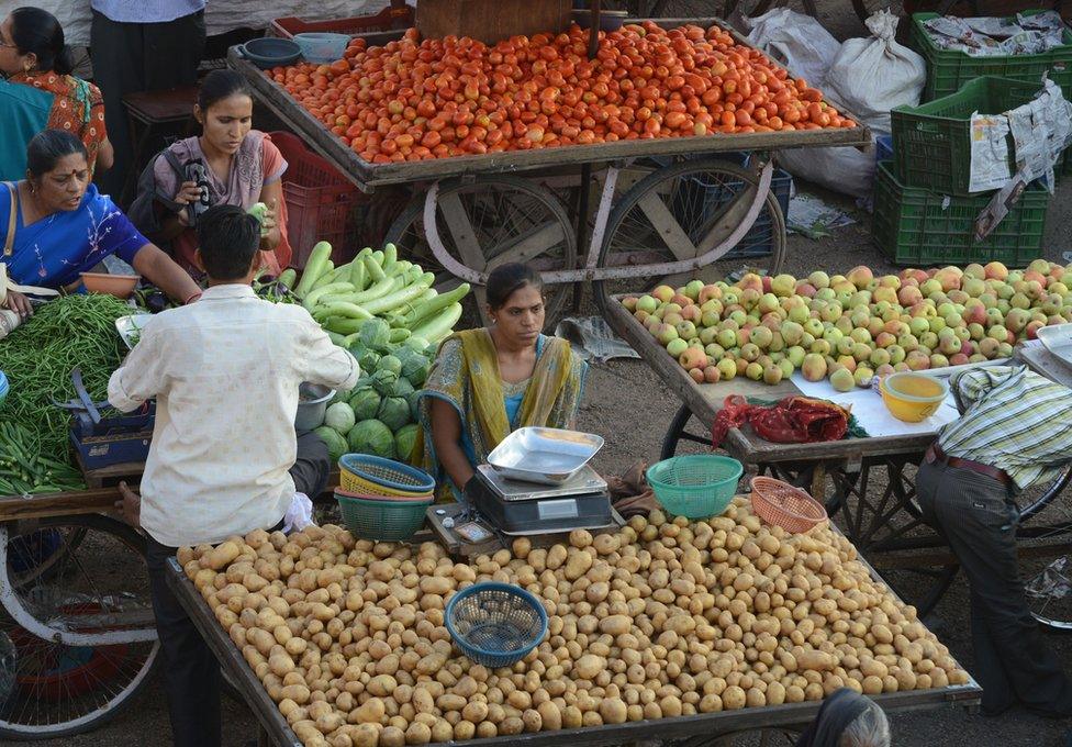 An Indian vegetable vendor (C) waits for customer at a market in Ahmedabad on October 22, 2013.