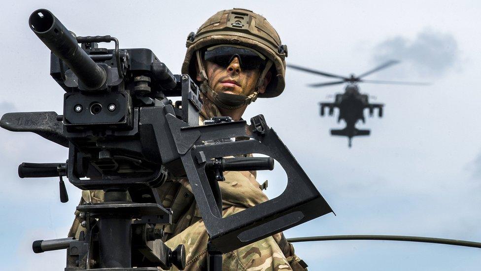 A helicopter hovering above a soldier