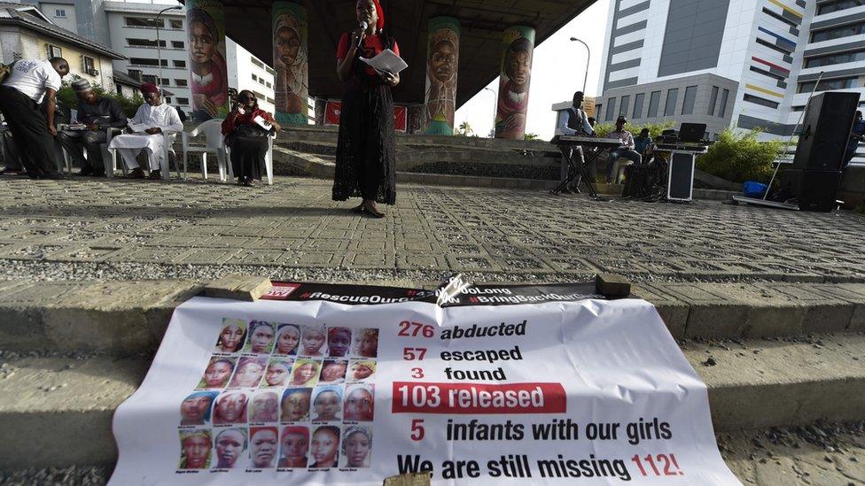 Aisha Oyebode. a founder of the Bring Back Our Girls movement speaks behind a banner with photographs of missing girls to press for the release of the remaining 112 Chibok schoolgirls at a vigil in Lagos on April 13, 2018.