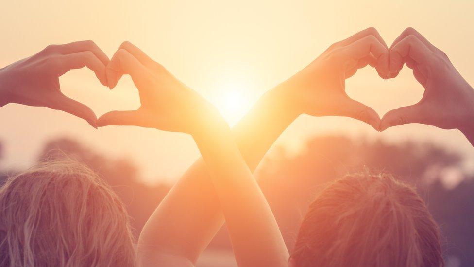 Two people making heart shapes with their hands