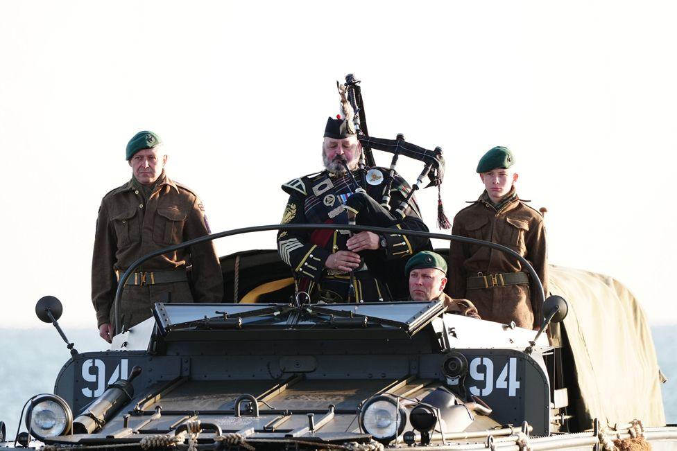 A military piper comes into shore on a DUKW amphibious vehicle ahead of playing a dawn lament on Gold Beach in Arromanches in Normandy, France, June 6, 2024.