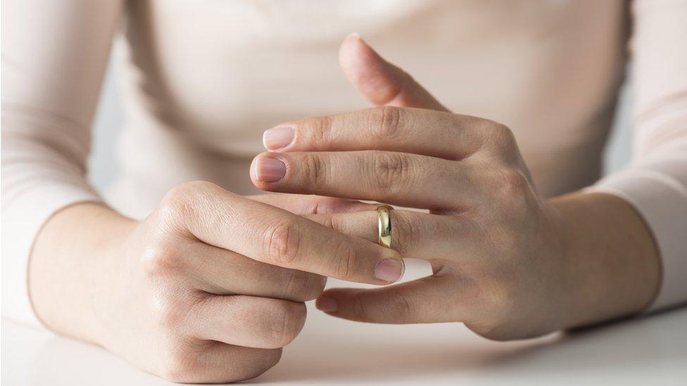 woman taking wedding ring off finger