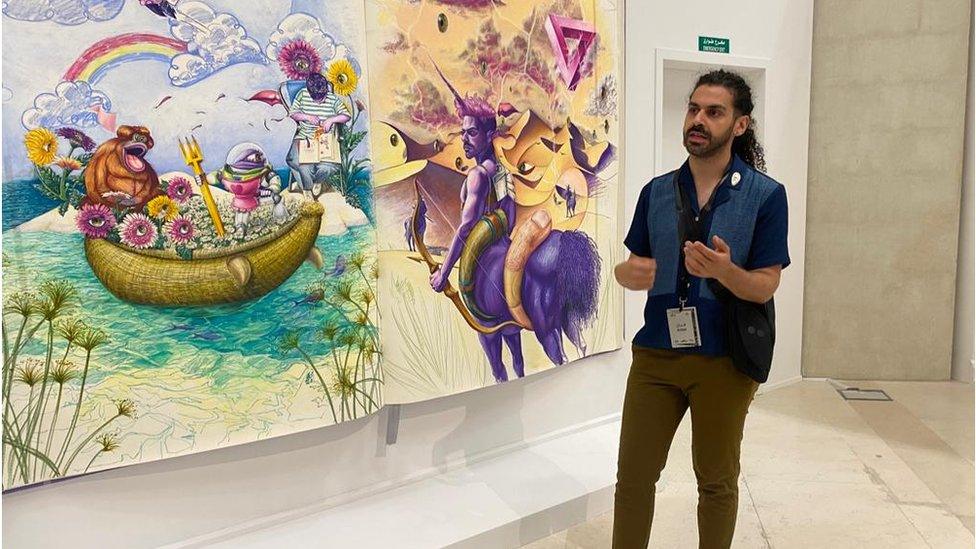 Artist Obadah Al-Jefri in front of paintings