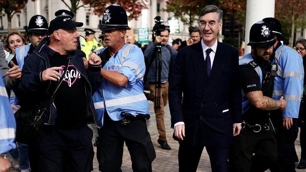 Police officers hold back members of the public as Business Secretary Jacob Rees-Mogg (right) arrives at the Conservative Party annual conference