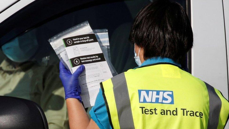 An NHS test and trace worker takes a coronavirus test to someone waiting in a vehicle