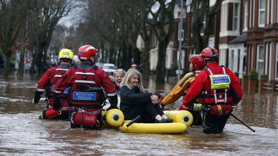 Emergency workers use an inflatable raft to rescue two women from flooding