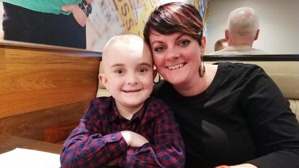 A young boy and his mum smile at the camera