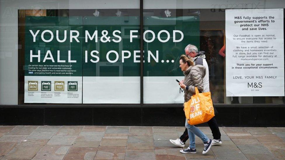 Couple walk past sign saying: "Your M&S food hall is open"