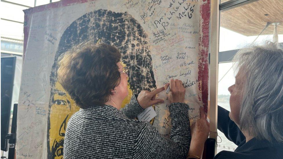 Mourners sign an anti-apartheid poster in Cardiff