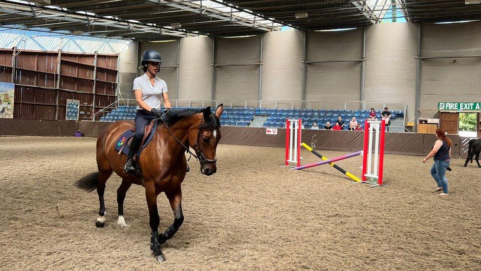 Woman riding a horse at an indoor arena