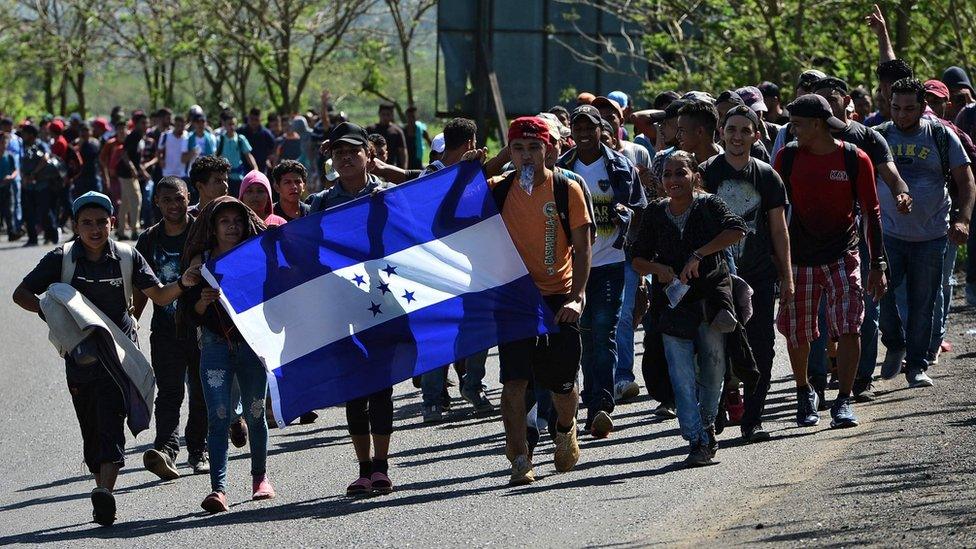 Honduran migrants walk with a Honduran national flag heading to Puerto Barrios, in Izabal department, Guatemala