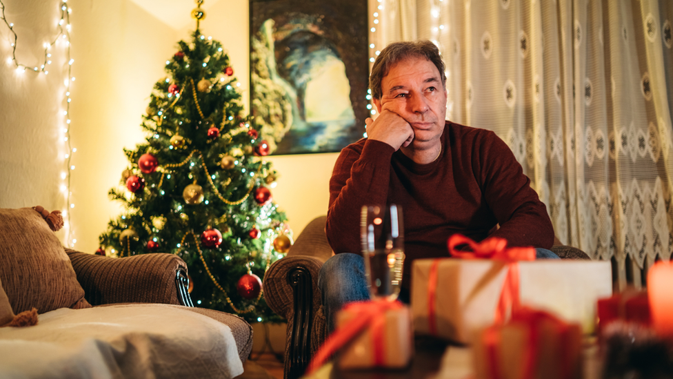 A man appears grumpy in a lounge at Christmas