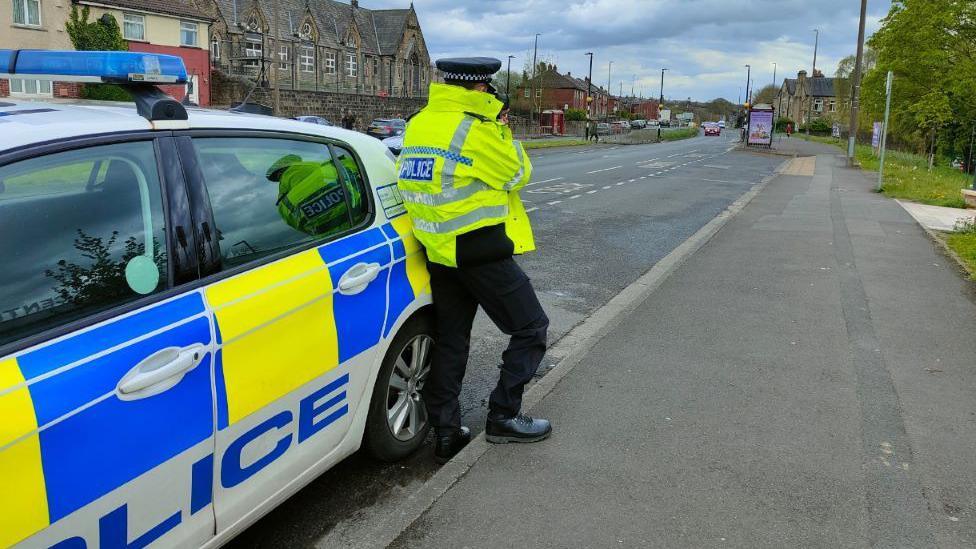 Police officer leaning against police car