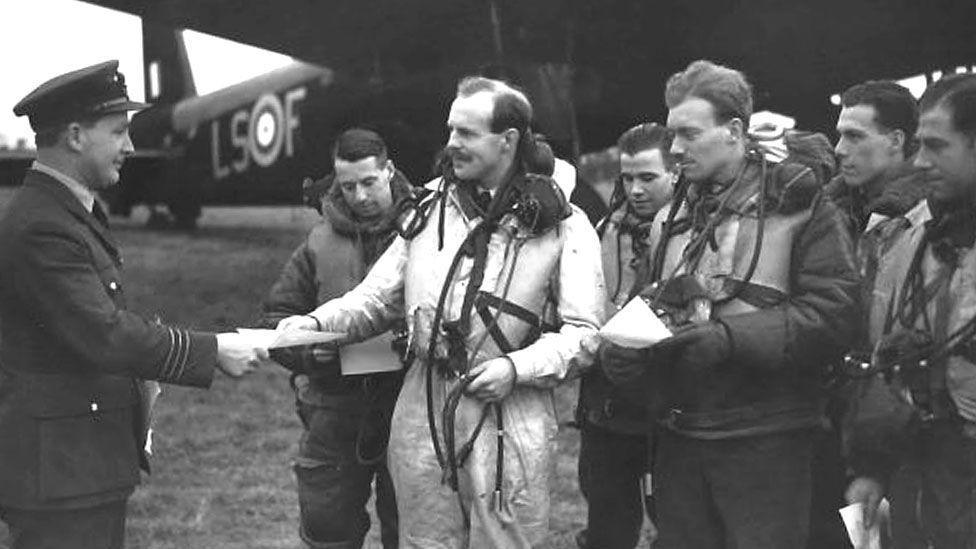Black and white image of RAF pilots in front of a plane.