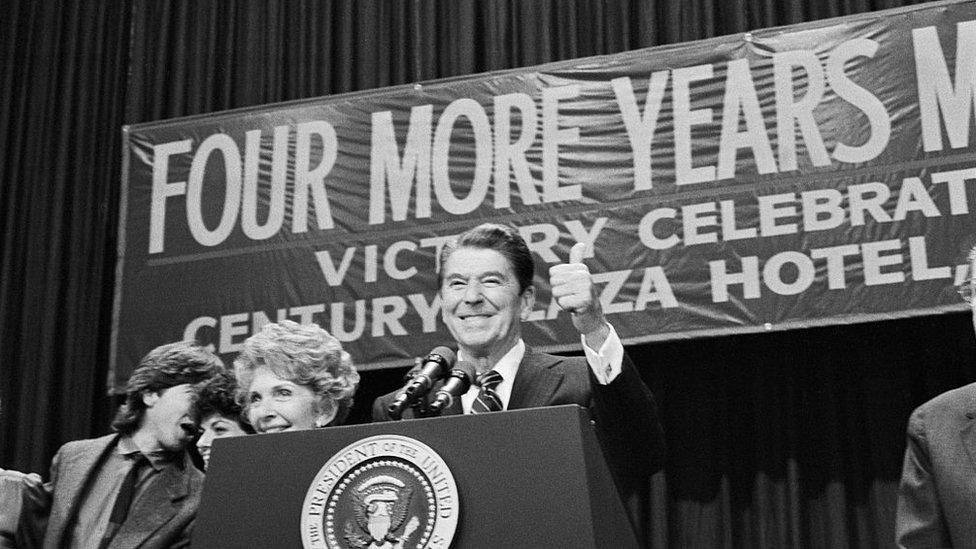 Ronald Reagan before a "four more years" sign