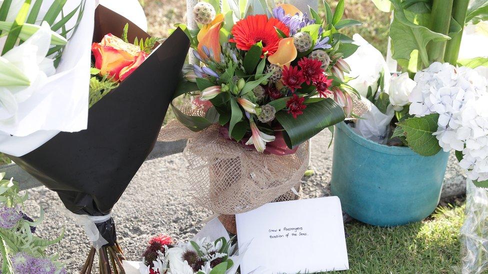 Floral tributes lie at the gates of the port where the cruise ship Ovation of the Seas is berthed, in Tauranga, New Zealand, 10 December, 2019.