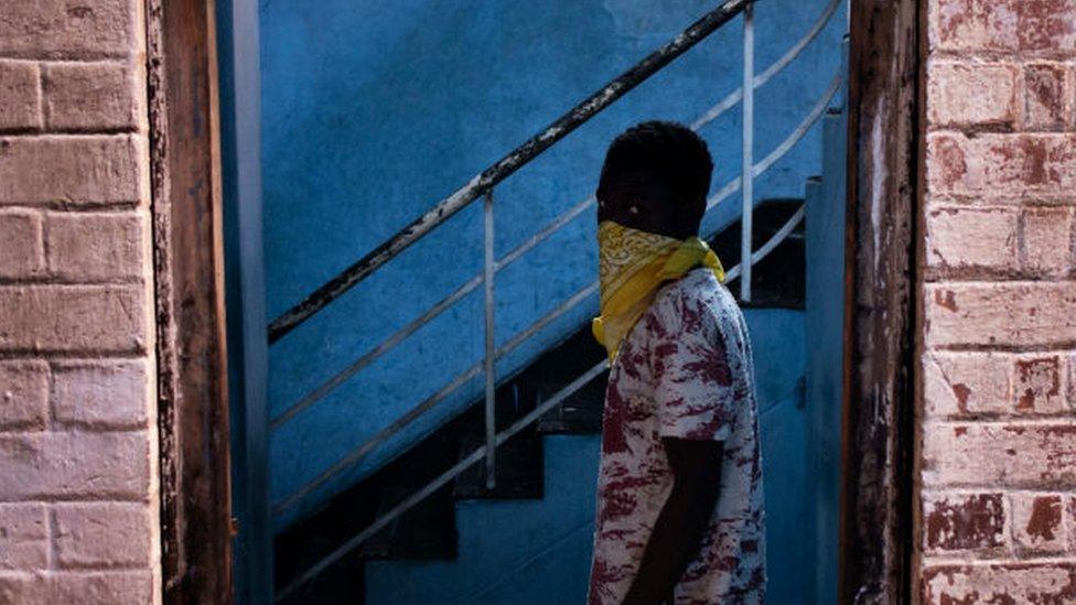 A foreign migrant wears a bandana as he leaves a building in the Kwa Mai Mai area in Johannesburg, on May 10, 2020.