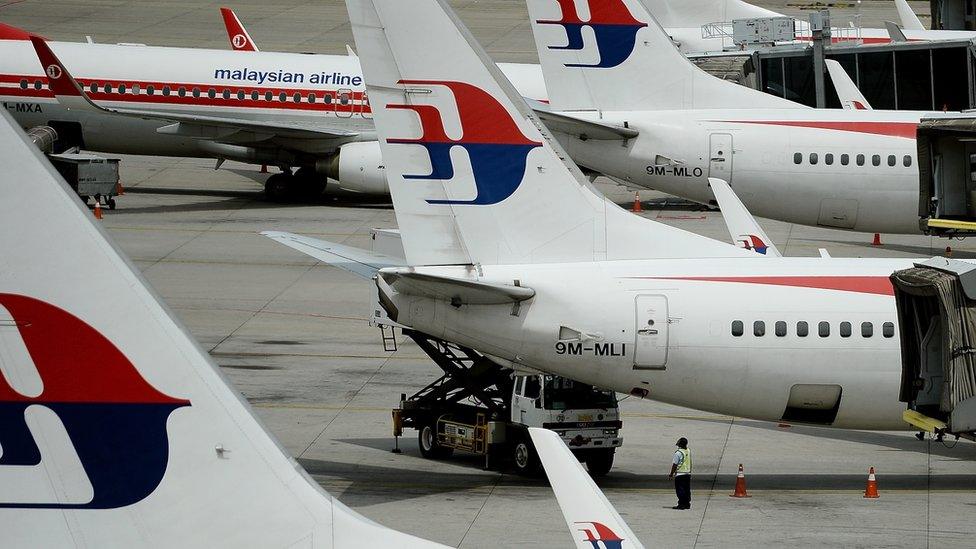 Malaysia Airlines ground staff walk past Malaysia Airlines aircraft parked on the tarmac at the Kuala Lumpur International Airport in Sepang on June 20, 2016.