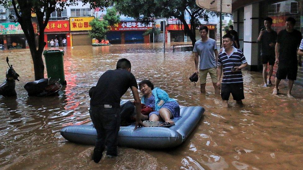 People wade in a flooded street on June 9, 2019 in Guilin, Guangxi