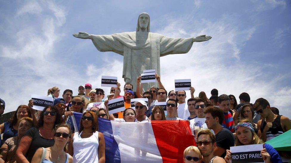 People hold "Rio est Paris" signs and the French flag