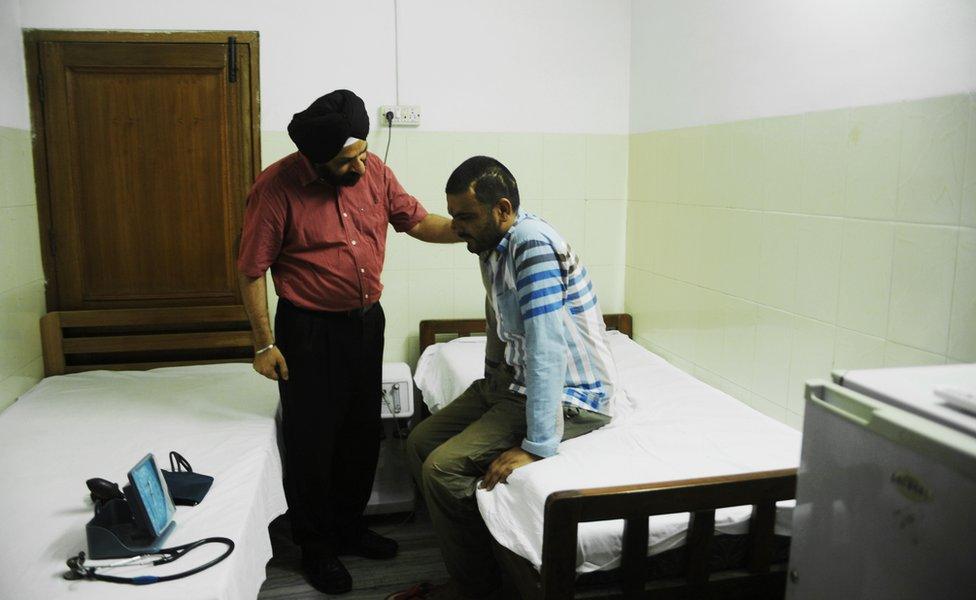 Indian doctor J.P.S. Bhatia (L) tends to recovering drug addict Amardeep Singh in Amristar on June 2, 2012