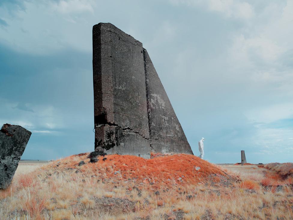 Scientist in protective clothing walks through landscape of a remote area of Kazakhstan used for nuclear testing