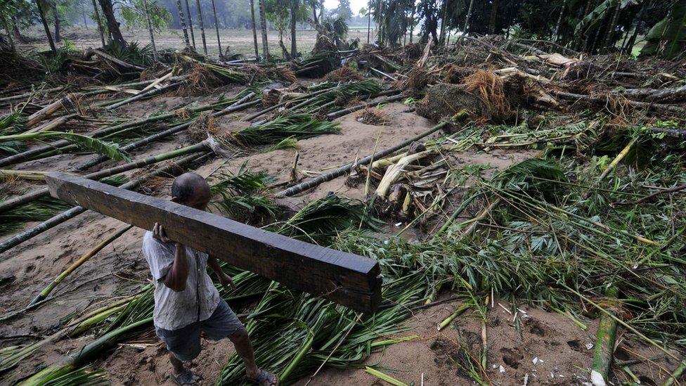 An Indian villager carries a salvaged plank in Meghalaya