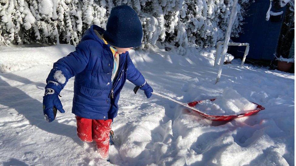 A child plays in the snow in a back garden in Belfast, Northern Ireland.