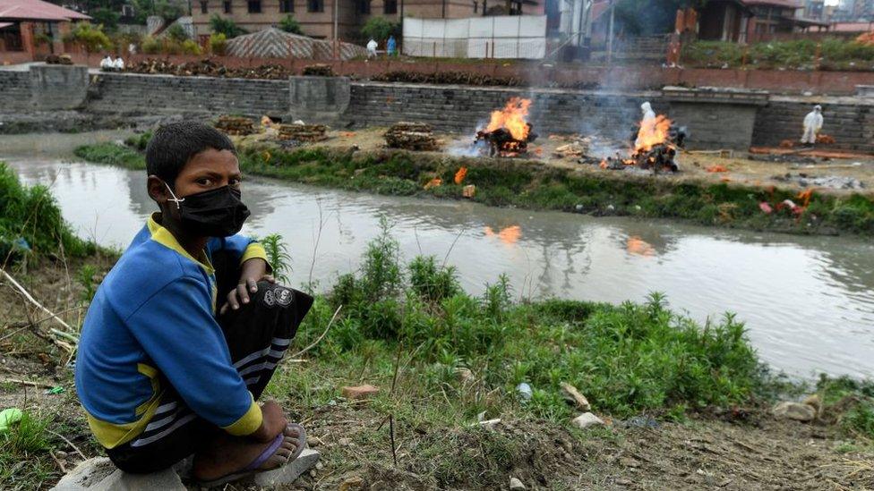 A boy watches funeral pyres of people who died due to Covid