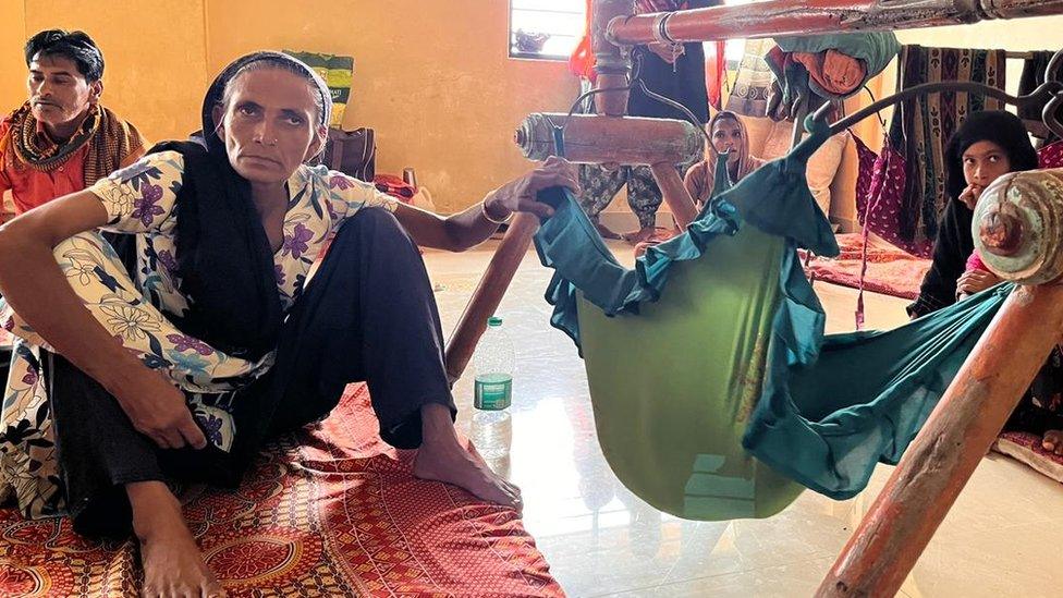 A woman next to baby's crib at a cyclone shelter in Mandvi