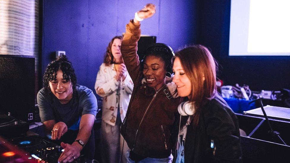 Four women DJing and smiling