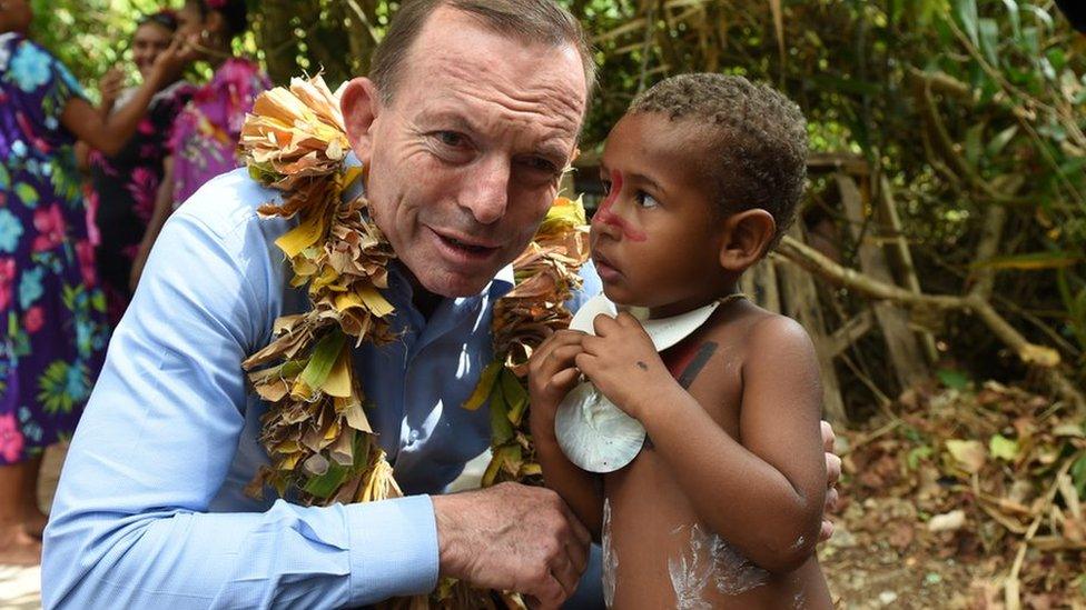 Australian Prime Minister Tony Abbott speaks with a child after laying a wreath on Eddie Mabo's grave on Mer Island in the Torres Strait