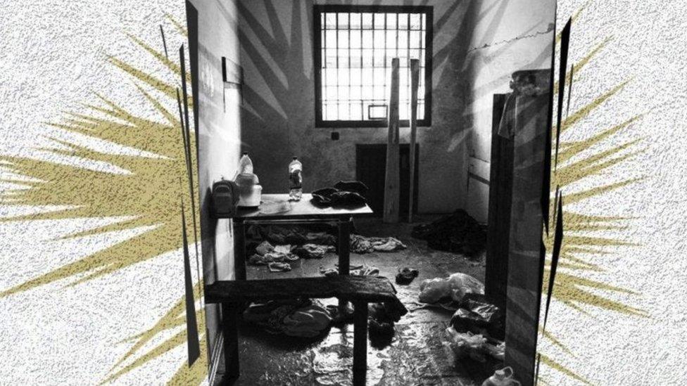 A prison cell with objects strewn around